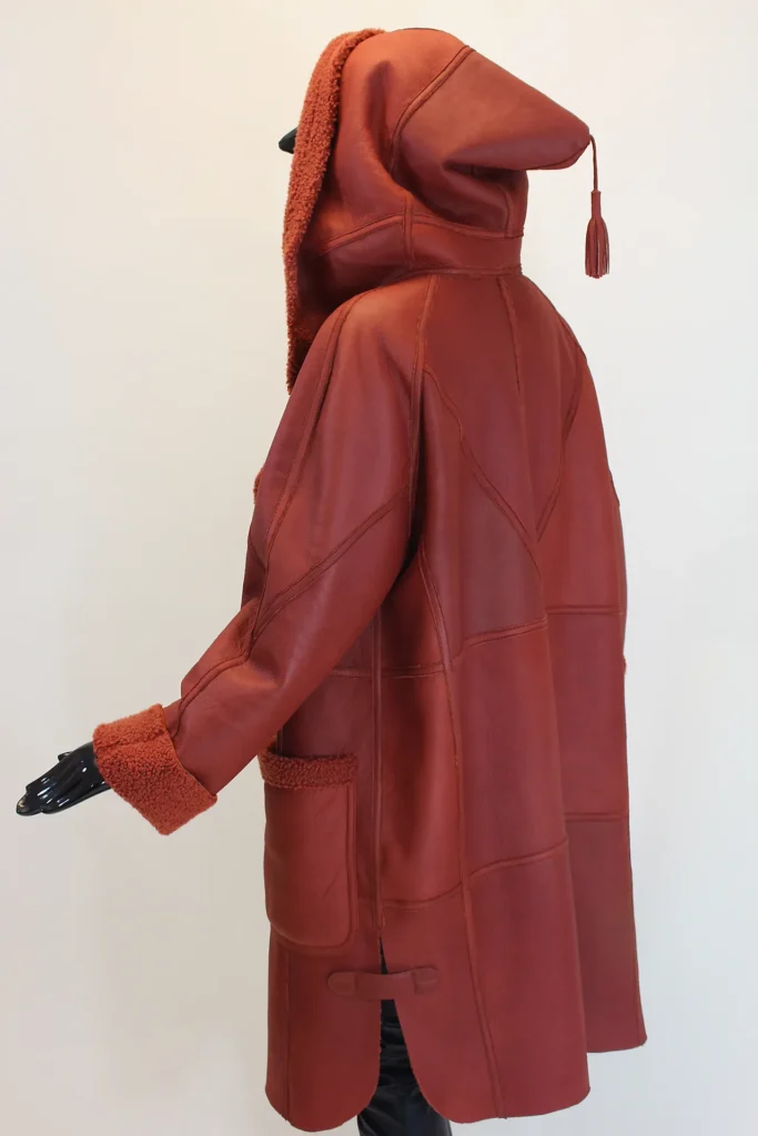 Mantel aus Currlylamm mit Kapuze und aufgesetzten Taschen.